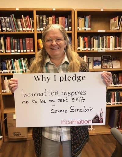 Woman holding a pledge sign in a library at Church of the Incarnation.