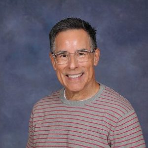 Portrait of a Smiling Man in a Striped Shirt Smiling man wearing glasses and a striped shirt against a blue background.